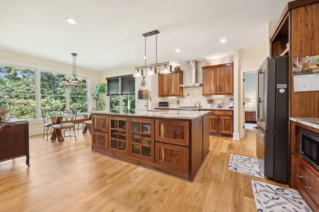 kitchen featuring appliances with stainless steel finishes, hanging light fixtures, wall chimney range hood, and a kitchen island