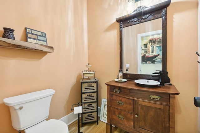 bathroom with wood-type flooring, vanity, and toilet