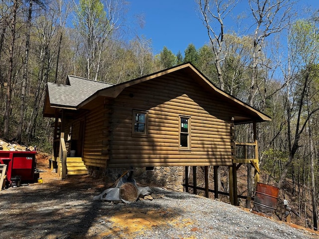 view of home's exterior with roof with shingles and log siding