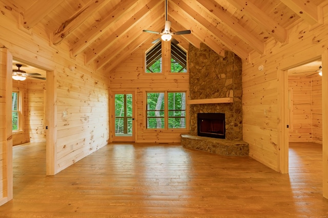 65 Christopher Dr, Ellijay, GA 30540 - unfurnished living room with a ceiling fan, wood-type flooring, wooden walls, a stone fireplace, and a wood ceiling with exposed beams