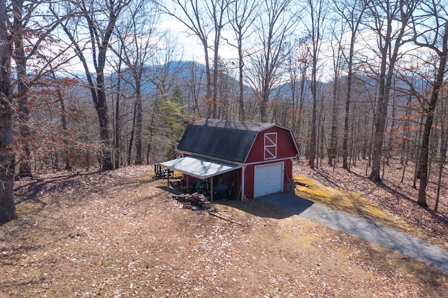 view of barn featuring a forest view and driveway