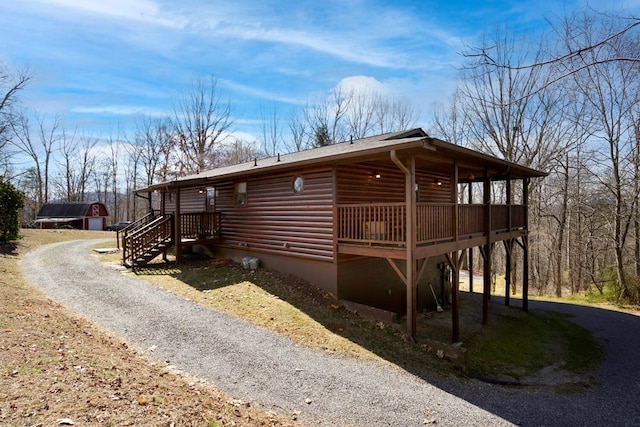 exterior space with gravel driveway, a wooden deck, and log veneer siding