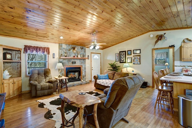 living room featuring vaulted ceiling, a stone fireplace, wooden ceiling, light wood-style floors, and a ceiling fan