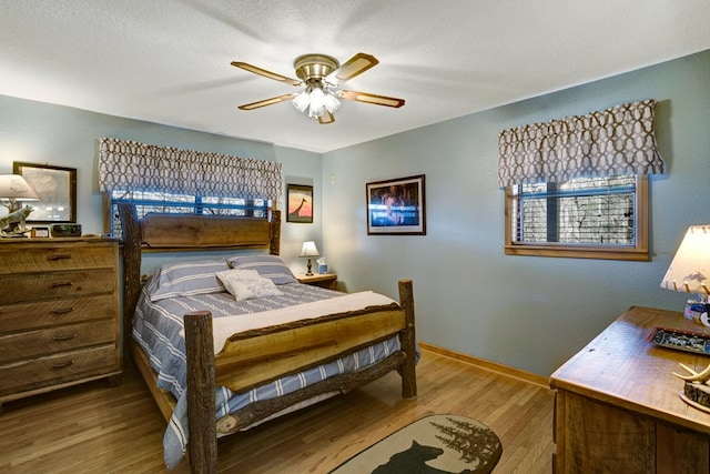 bedroom featuring a textured ceiling, a ceiling fan, baseboards, and wood finished floors