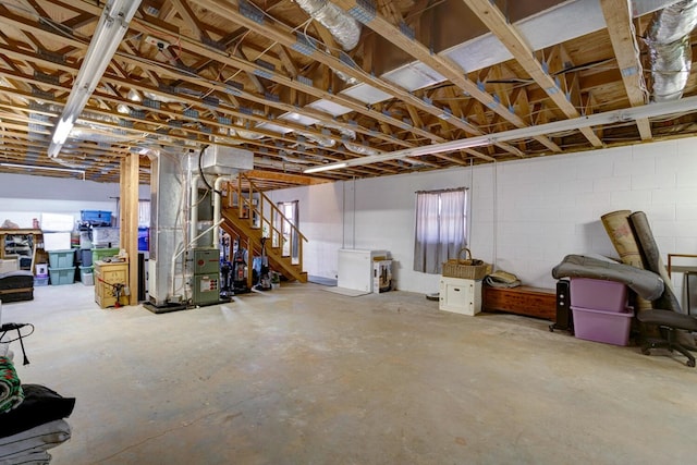 basement with heating unit, concrete block wall, and stairs
