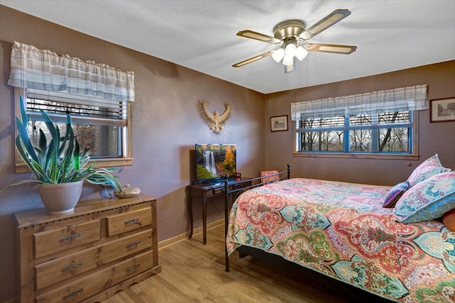 bedroom featuring a ceiling fan, baseboards, and light wood finished floors