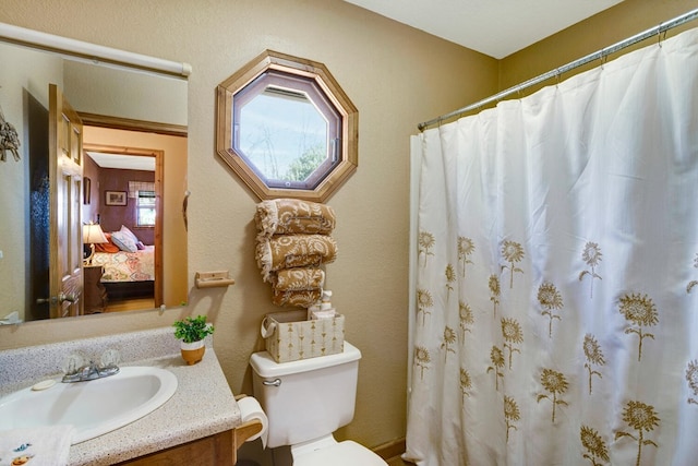 full bath featuring connected bathroom, toilet, a shower with shower curtain, a textured wall, and vanity