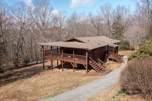 back of property with stairway, a yard, roof with shingles, a wooden deck, and log siding