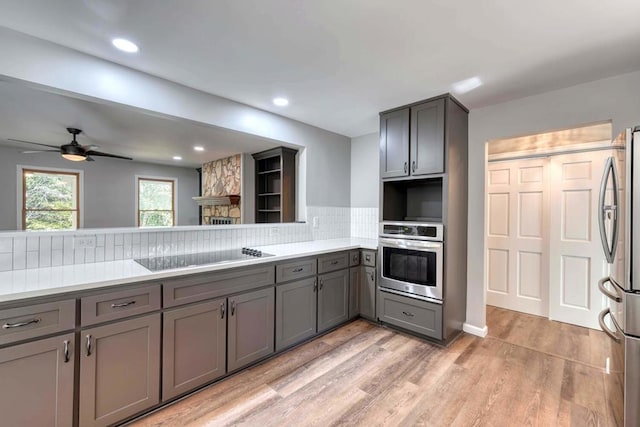 kitchen with ceiling fan, gray cabinetry, backsplash, stainless steel appliances, and light hardwood / wood-style floors