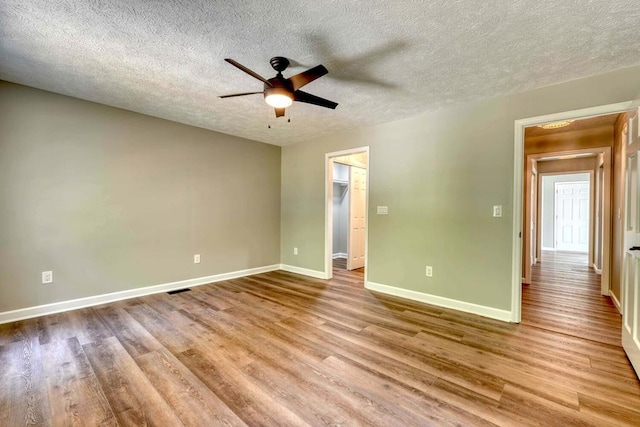 unfurnished bedroom with a spacious closet, ceiling fan, and light wood-type flooring