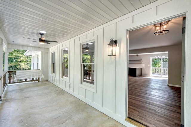 unfurnished sunroom featuring a healthy amount of sunlight and ceiling fan with notable chandelier