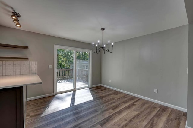 unfurnished dining area with wood-type flooring and a chandelier