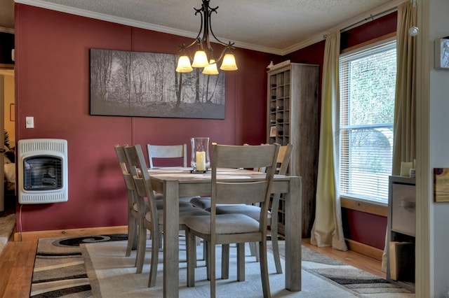 dining room with light hardwood / wood-style flooring, a notable chandelier, heating unit, a textured ceiling, and ornamental molding