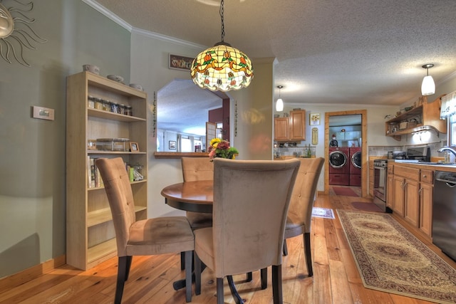 dining room with washing machine and dryer, sink, vaulted ceiling, and light wood-type flooring