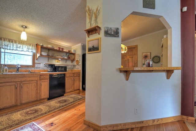 kitchen with black appliances, decorative light fixtures, and light wood-type flooring