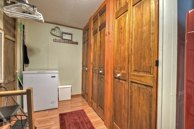 washroom with a textured ceiling, light hardwood / wood-style flooring, and crown molding