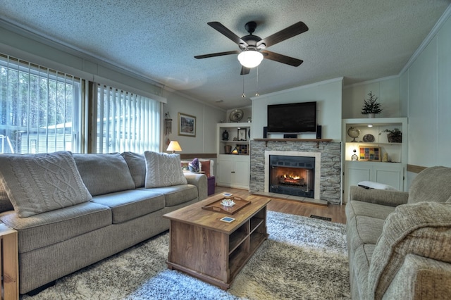 living room featuring crown molding, light hardwood / wood-style flooring, ceiling fan, a textured ceiling, and a fireplace