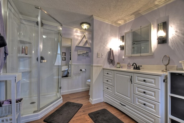 bathroom with crown molding, wood-type flooring, a textured ceiling, toilet, and a shower with shower door