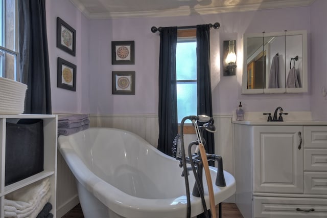 bathroom with vanity, ornamental molding, and a tub