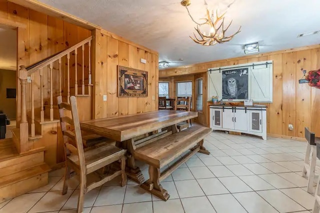 dining space featuring a notable chandelier, stairway, wood walls, and light tile patterned flooring