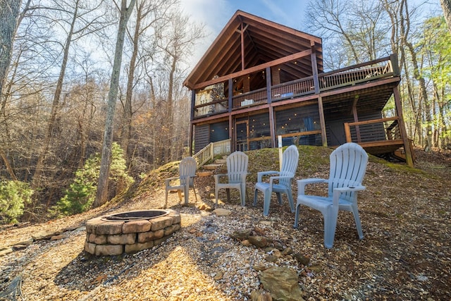 rear view of property featuring a deck and a fire pit