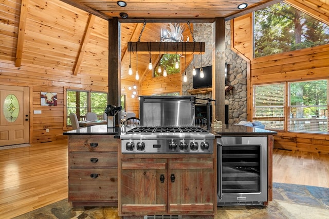 kitchen with wine cooler, stainless steel gas cooktop, wooden ceiling, wooden walls, and beam ceiling