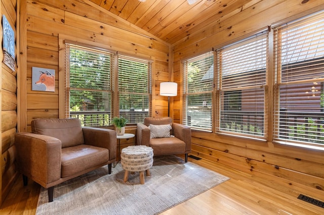 living area with hardwood / wood-style flooring, vaulted ceiling, wooden ceiling, and wood walls