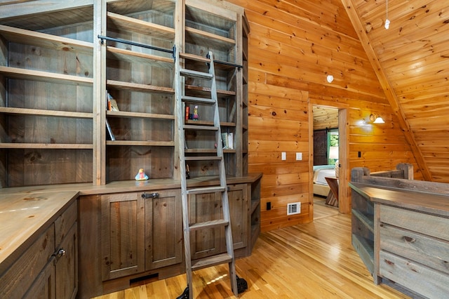 interior space featuring vaulted ceiling, wooden ceiling, wooden walls, and light hardwood / wood-style floors