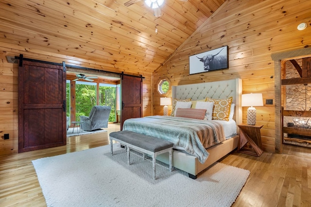 bedroom featuring light hardwood / wood-style floors, a barn door, and wood walls