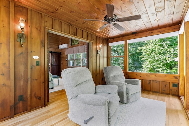 sitting room featuring ceiling fan, a wall mounted AC, light hardwood / wood-style floors, wooden ceiling, and wood walls