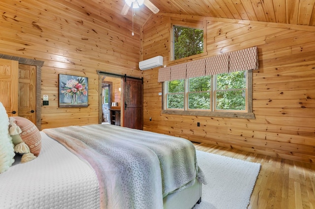 bedroom featuring ceiling fan, a barn door, a wall mounted air conditioner, and wooden walls