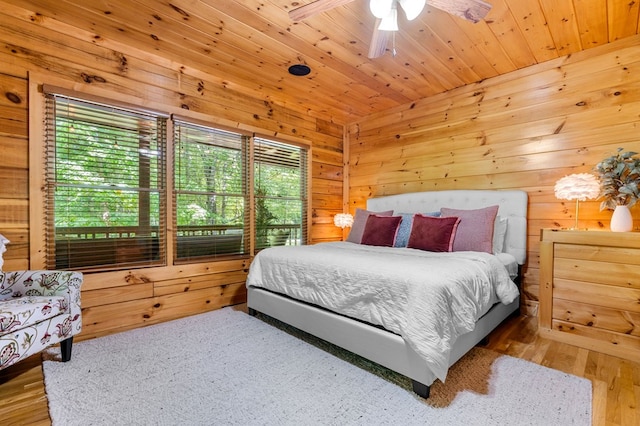 bedroom with hardwood / wood-style floors, wooden walls, wooden ceiling, and ceiling fan