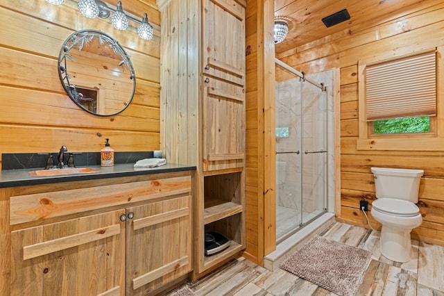 bathroom featuring hardwood / wood-style floors, vanity, a shower with shower door, toilet, and wood walls