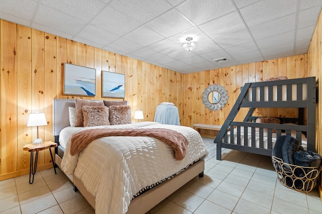 tiled bedroom featuring a paneled ceiling and wood walls