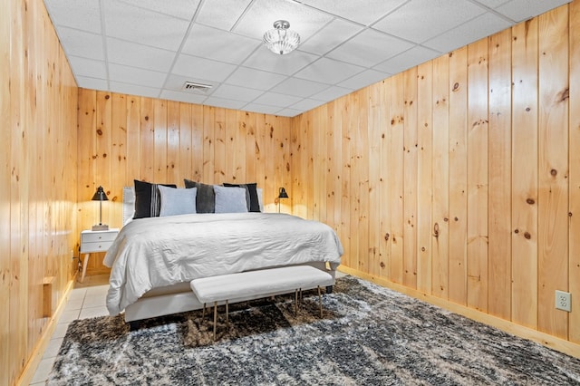 bedroom featuring a paneled ceiling and wooden walls