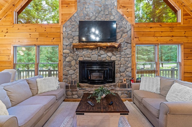 living room featuring plenty of natural light, a fireplace, high vaulted ceiling, and wood walls