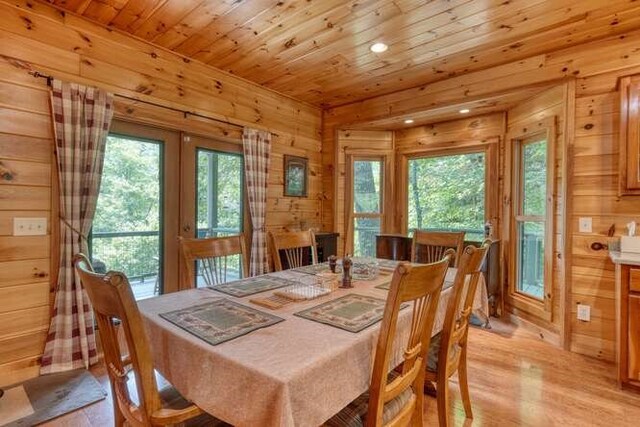 living room with plenty of natural light, high vaulted ceiling, wood walls, and a stone fireplace