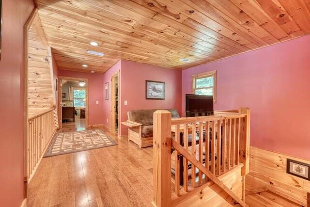 dining room featuring light wood-type flooring, wooden walls, and wooden ceiling