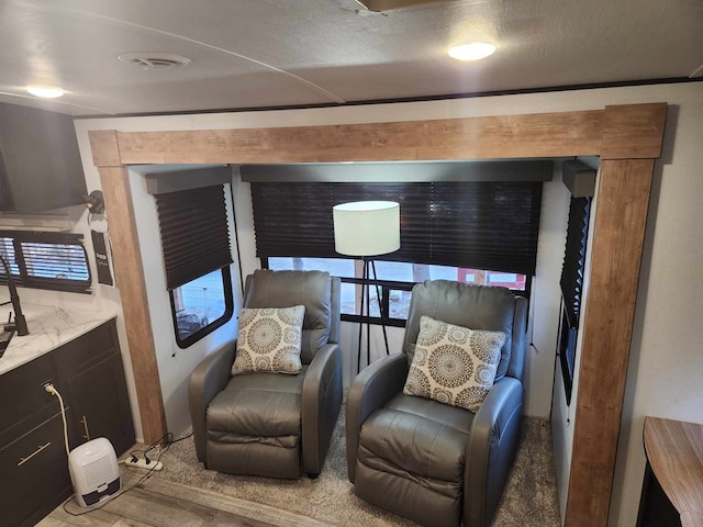 living area featuring visible vents and wood finished floors