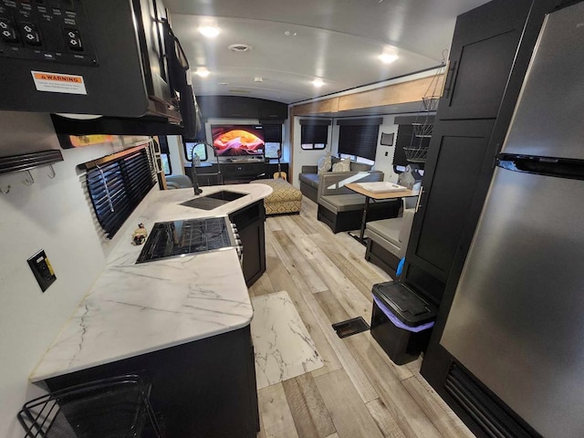 kitchen with lofted ceiling, light wood-style floors, a sink, and dark cabinetry