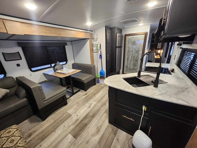 interior space with light wood-style flooring, visible vents, light stone counters, and dark cabinets