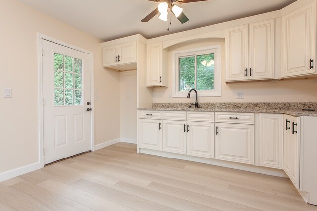 kitchen featuring light stone countertops, sink, light wood-type flooring, and ceiling fan