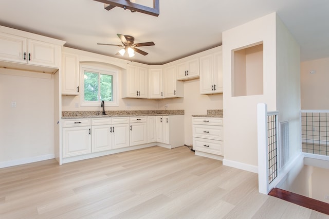 kitchen featuring white cabinetry, light wood-type flooring, ceiling fan, and light stone countertops