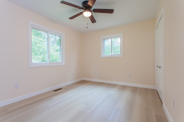 spare room with light hardwood / wood-style floors, a wealth of natural light, and ceiling fan