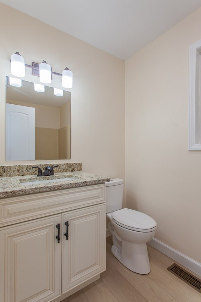 bathroom featuring vanity, hardwood / wood-style flooring, and toilet