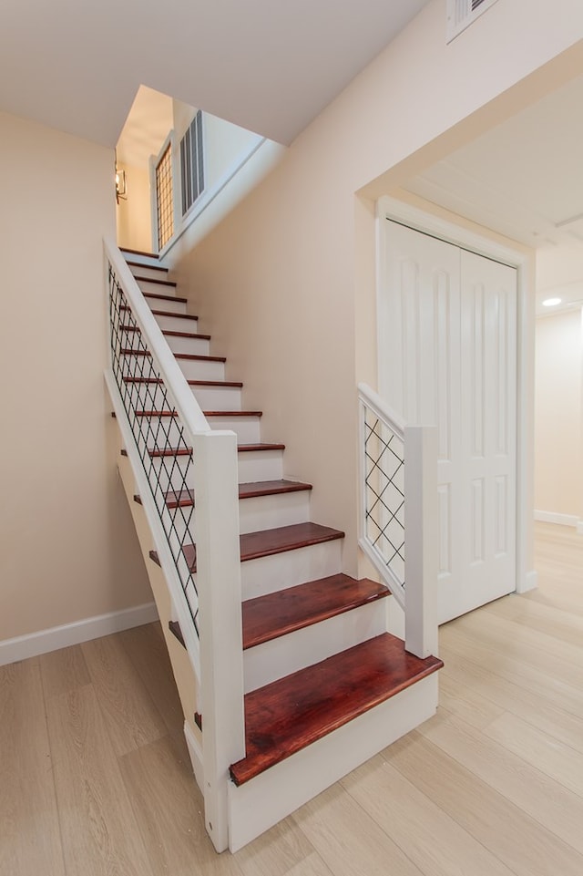 stairway with light hardwood / wood-style floors