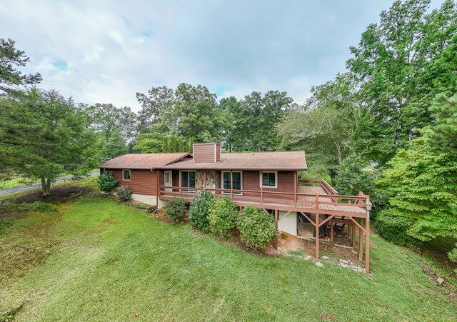 rear view of house with a lawn and a wooden deck