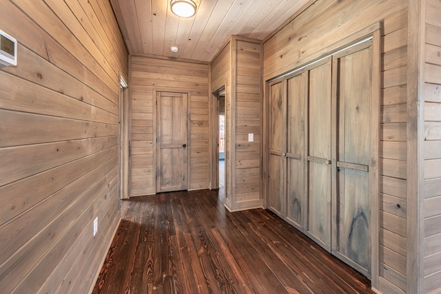 corridor featuring dark wood-type flooring, wooden walls, and wooden ceiling