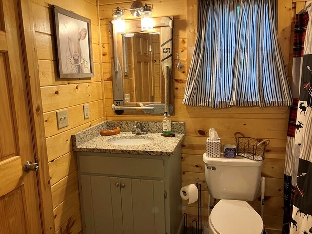 bathroom featuring vanity, toilet, and wood walls