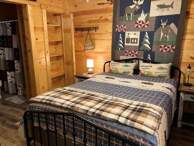 bedroom with wood walls, dark hardwood / wood-style flooring, and a closet